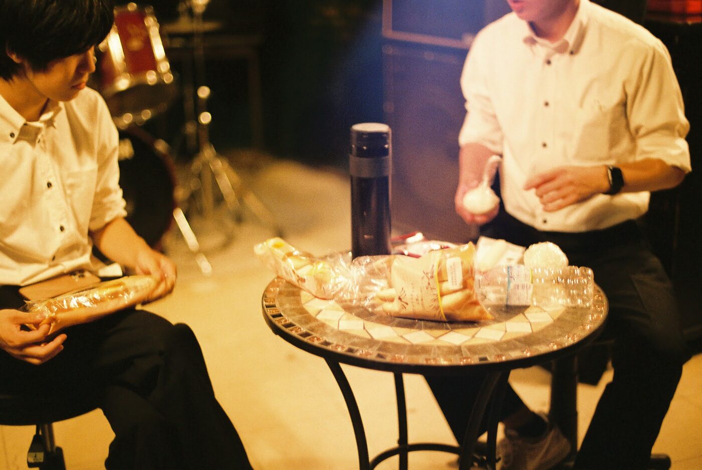 ライブ会場の楽屋、テーブルを挟んで談笑する2人